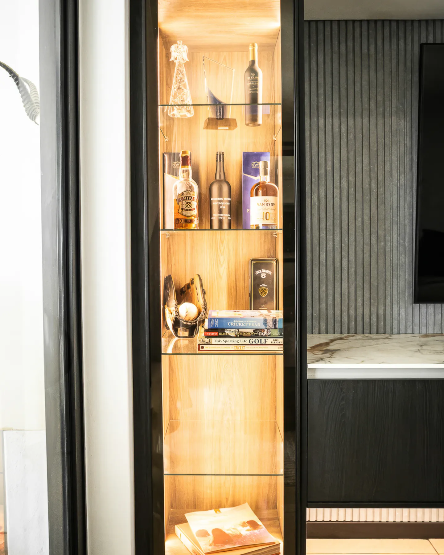 Lit glass display cabinet next to the fluted wall panel