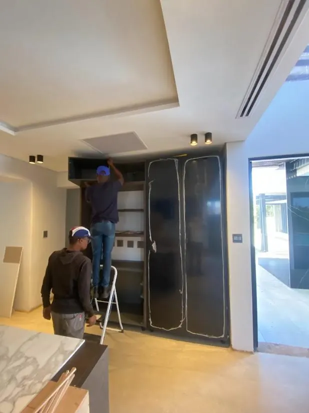 Team installing glass-fronted cabinetry on site